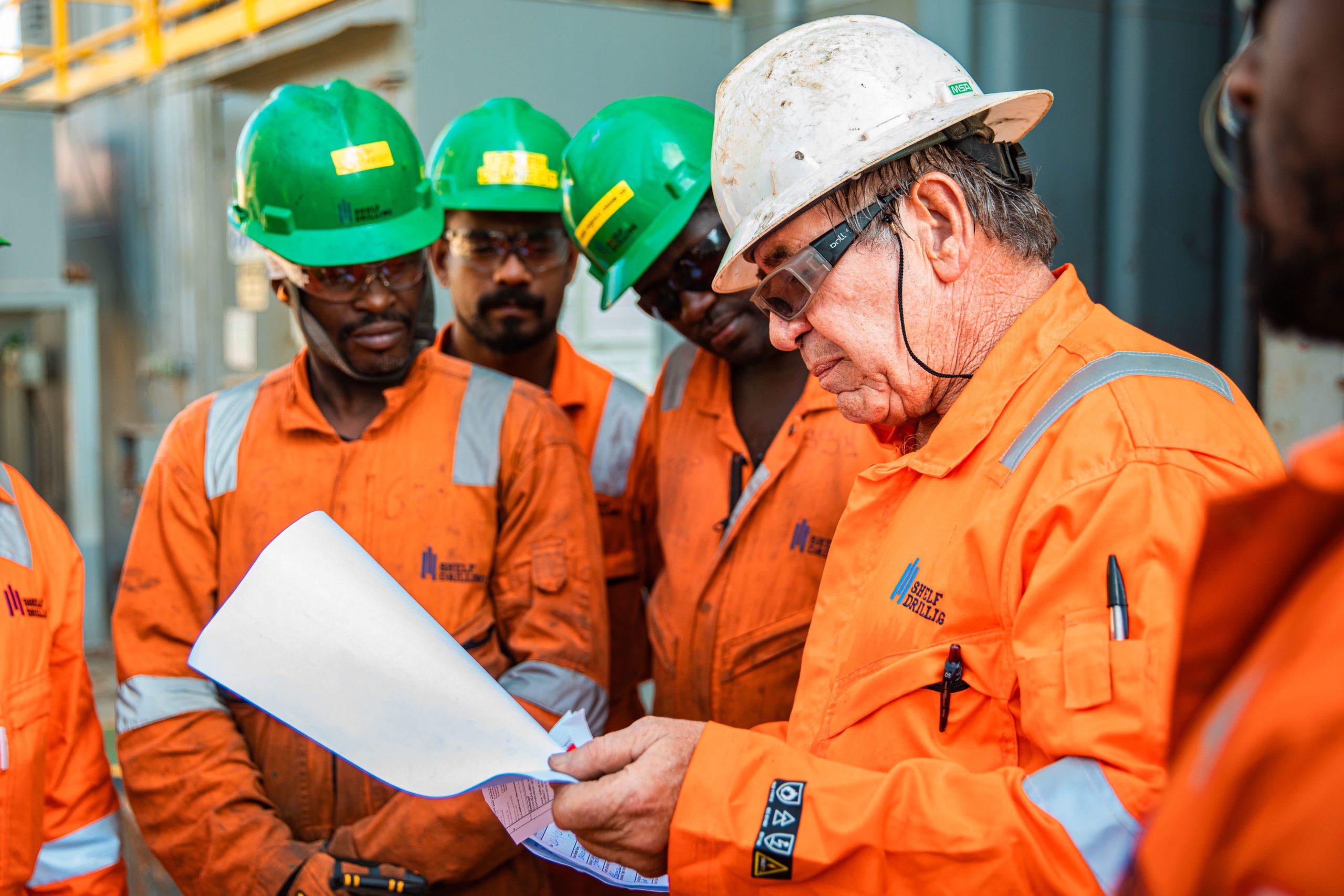 Industrial photography in UAE representing industrial workers team with hard tops being briefed for work.